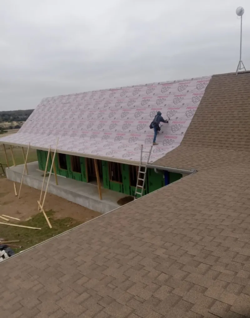 Worker preparing underlayment for a metal roof installation in Lockwood